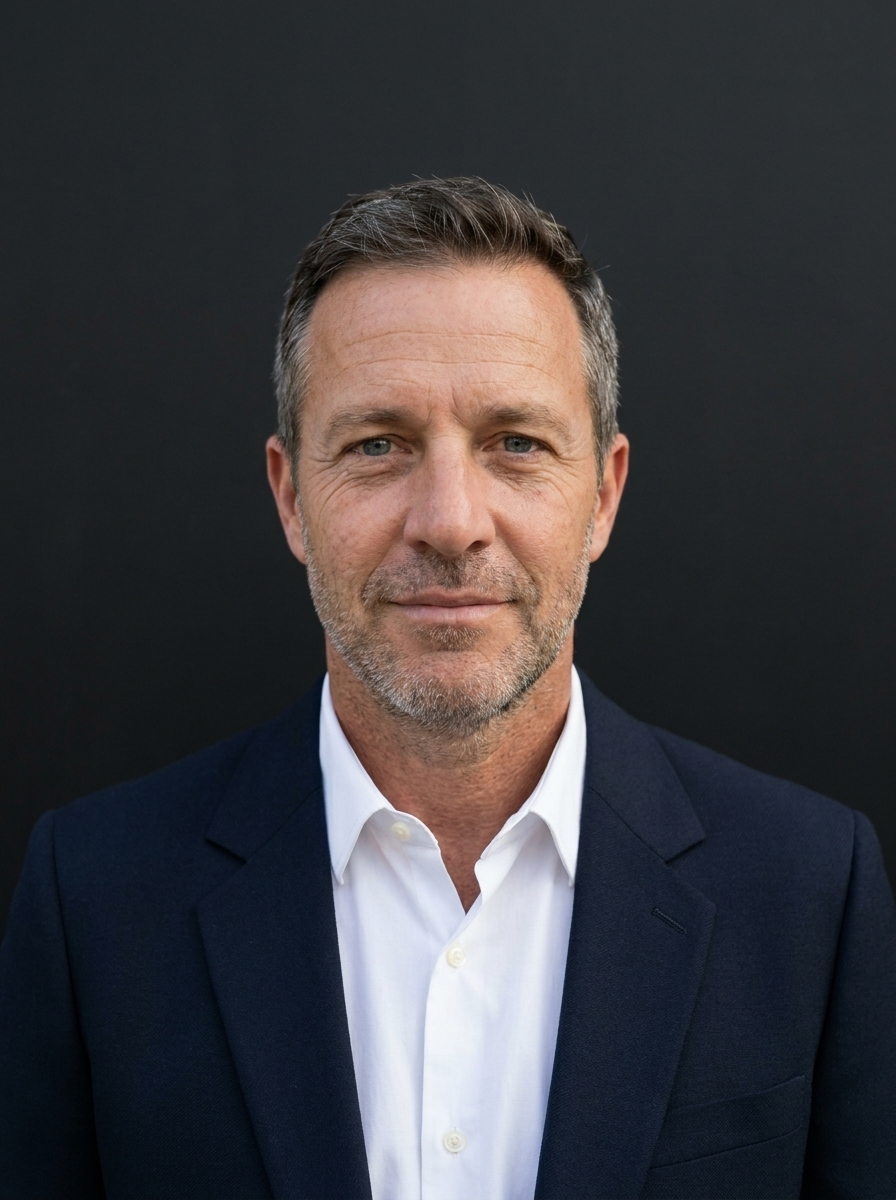 After — editorial portrait of the same man in navy blazer and white poplin, dark studio